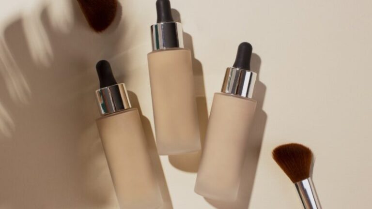 trzy buteleczki podkładu do twarzy na białym tle