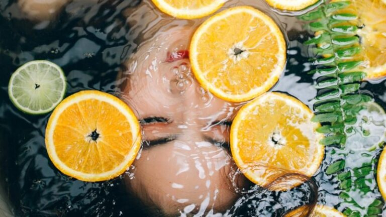 kobieca twarz pod wodą i plastrami cytryny