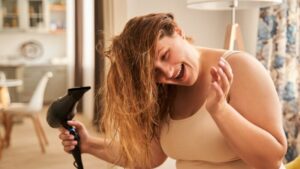 Kobieta susząca włosy suszarką