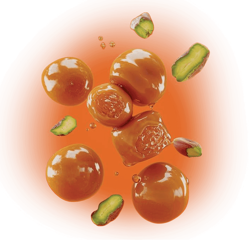 Słony karmel i pistacja sycylijska: kulki karmelu oraz zielone orzechy na pomarańczowym tle.